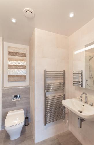 a bathroom with a toilet and a sink at 11 Woolacombe West - Luxury Apartment at Byron Woolacombe, only 4 minute walk to Woolacombe Beach! in Woolacombe