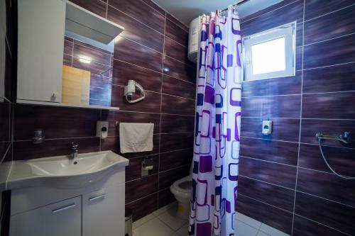 a bathroom with a sink and a shower curtain at Motel Aura in Mostar