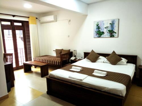 Habitación de hotel con cama y banco. en Sarvodaya Samma Vaasa Residence, en Kandy