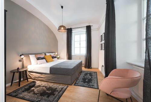 a bedroom with a bed and a pink chair at Apartments Rog in Ljubljana