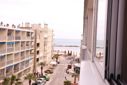 Blick aus einem Hotelfenster auf eine Straße und das Meer in der Unterkunft Studio Palavas proche plage in Palavas-les-Flots