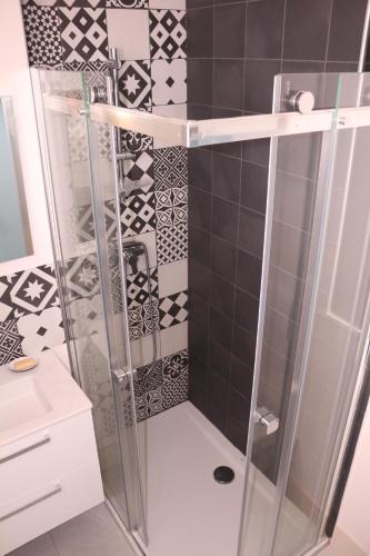 eine Dusche im Bad mit schwarzen und weißen Fliesen in der Unterkunft Studio Palavas proche plage in Palavas-les-Flots