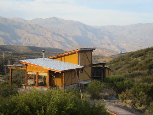 a small yellow house with mountains in the background at Cabaña La Mostacita - Complejo El Taller in Potrerillos