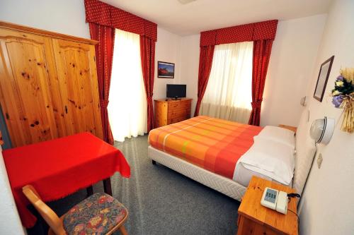 Hotel Capitani في بورميو: غرفة نوم بسرير ومكتب وكرسي