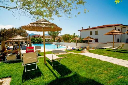 einen Garten mit Stühlen und Sonnenschirmen sowie einem Pool in der Unterkunft Villasulizzu in Budoni