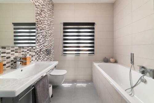 a bathroom with a tub and a toilet and a sink at Villa Bella with Private Pool and Hot Tub in Lardos
