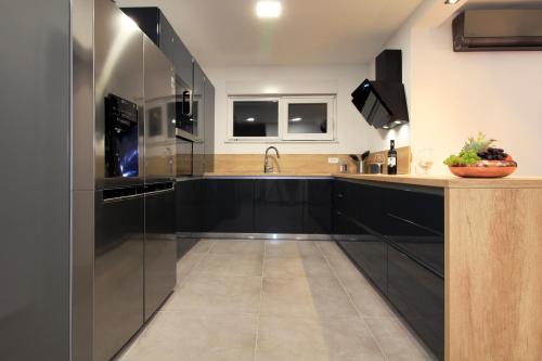 uma cozinha com armários pretos e um lavatório em Villa Navis HEATED POOL em Makarska