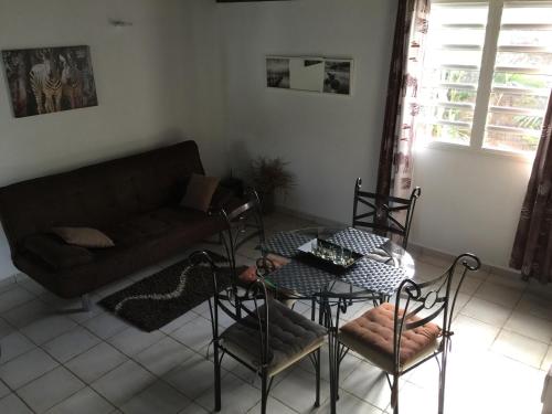 a living room with a table and chairs and a couch at Résidence les Kalbassiers in Lamentin