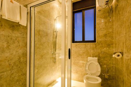 a bathroom with a toilet and a glass shower at The Venti Hotel & Spa in Kampala