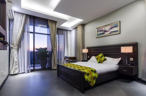 um quarto com uma cama e uma grande janela em The Venti Hotel & Spa em Kampala