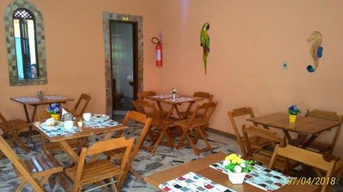 um restaurante com mesas e cadeiras de madeira e um papagaio na parede em Pousada Montreux na Praia do Forte