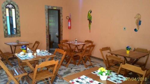 a restaurant with wooden tables and chairs and a parrot on the wall at Pousada Montreux in Praia do Forte