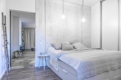 a white bedroom with a large bed and a table at Mazurska 110 in Rydzewo