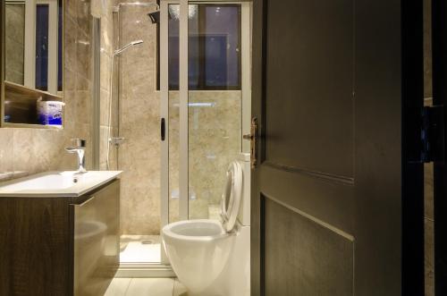 a bathroom with a shower and a toilet and a sink at The Venti Hotel & Spa in Kampala