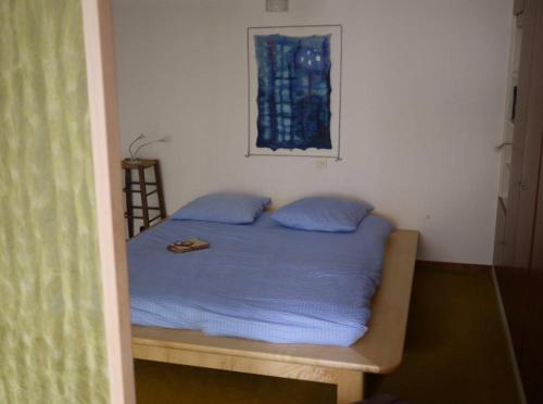 Una cama con almohadas azules en una habitación pequeña. en Casa Rabissale, en Locarno