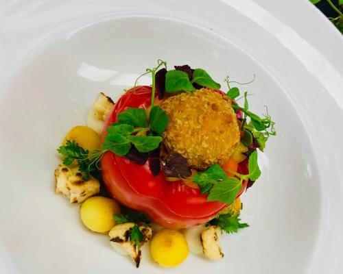 a plate of food with a tomato and other vegetables at Hotel Lauterbad in Freudenstadt