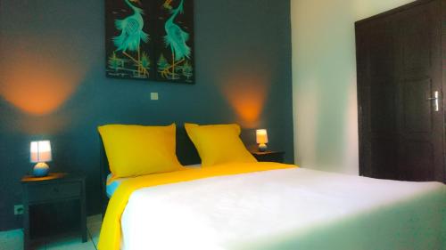 a bedroom with a bed with two yellow pillows at La Maison in Toamasina