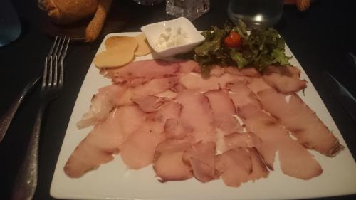 a plate of food with meat and vegetables on a table at La Maison in Toamasina