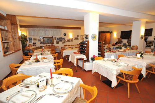 a restaurant with tables and chairs with white table cloth at Hotel Derby in Bormio