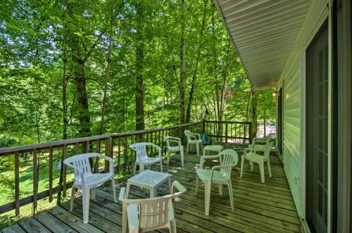a porch with white chairs and tables and trees at Nantahala Cabins in Bryson City
