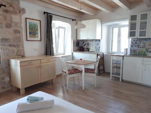 a kitchen with white cabinets and a table and chairs at House at the seafront in Stari Grad