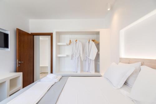 una camera da letto bianca con abiti bianchi appesi ad uncini di Akis Luxury House ad Adámas