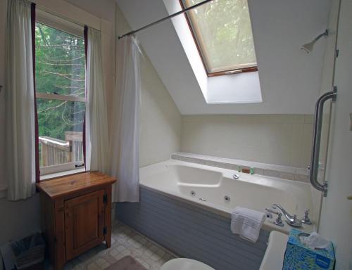 bagno con vasca, lavandino e finestra di The Wilmington Inn a Wilmington