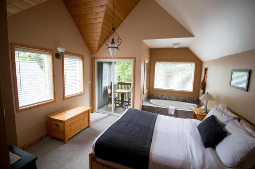 a bedroom with a bed and a bath tub and a bed sidx sidx sidx sidx at Reef Point Cottages in Ucluelet