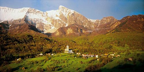 a house on a hill with a mountain in the background at Tourist Farm Kranjc in Kobarid