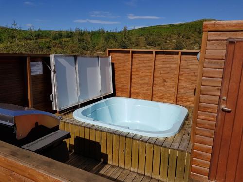a bath tub sitting on a deck next to a refrigerator at Gljúfurbústaðir Holiday Homes in Hveragerði