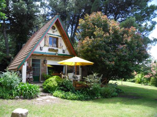 a small house with an umbrella in the yard at Cabañas Ñuke Mapu in Villa Ventana
