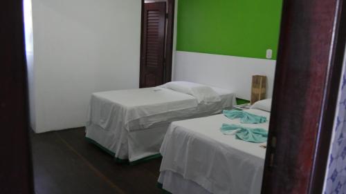 a room with two beds and a green wall at Pousada Maramazon in São Luís