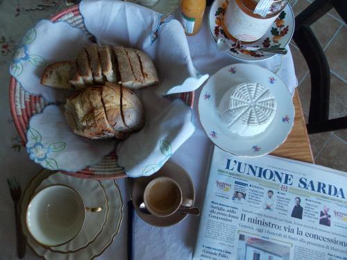 a plate of bread and a cup of coffee and a newspaper at B&B PIBITZOI in Nurallào