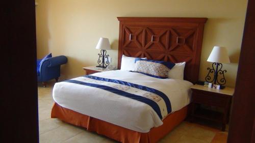 a bedroom with a large bed with a wooden headboard at Suites at PB Sunset Beach Cabo San Lucas in Cabo San Lucas