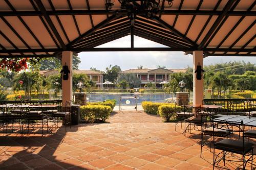 a patio with tables and chairs and a pool at Hotel Campestre Cafe Cafe in Montenegro