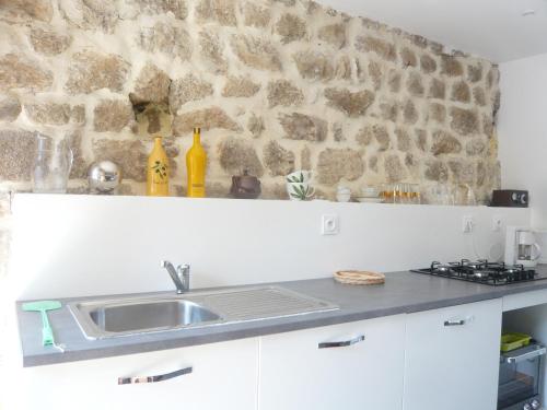 a kitchen with a sink and a stone wall at L'Ancienne Ecole in Silhac