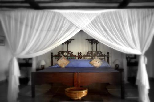 a bedroom with a bed with a canopy at Amani Beach Resort in Kutani