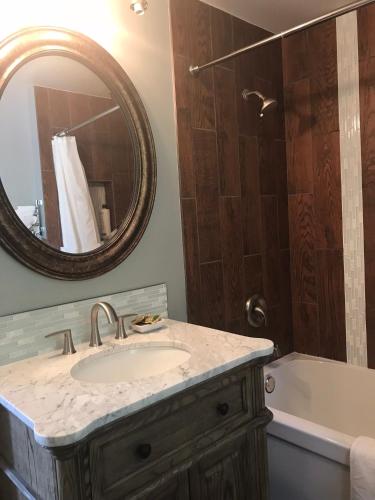 a bathroom with a sink and a tub and a mirror at The Gables Inn in Sarnia