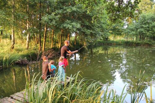 a man and three children fishing in a pond at Domek Drewniany in Nowa Wola