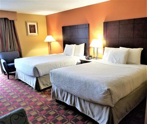 a hotel room with two beds and a chair at Howard Johnson by Wyndham Clifton NJ in Clifton