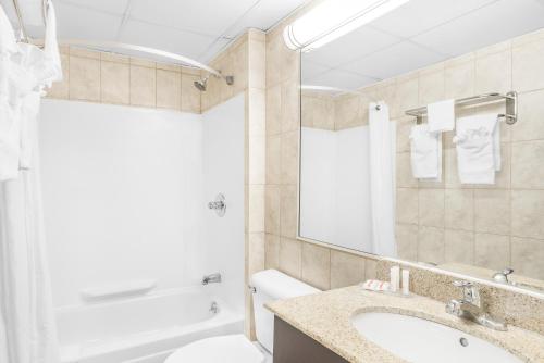 y baño con bañera, lavabo y espejo. en Howard Johnson by Wyndham Clifton NJ, en Clifton