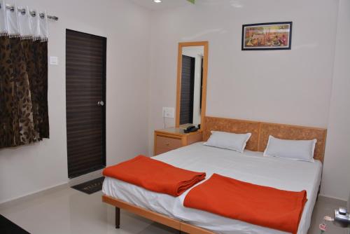 a bedroom with a bed with an orange blanket at Hotel neptune in Amreli