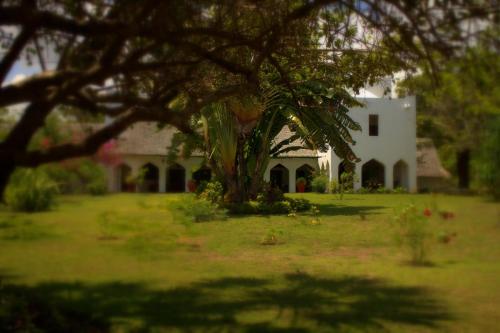 a white house with a tree in the yard at Amani Beach Resort in Kutani