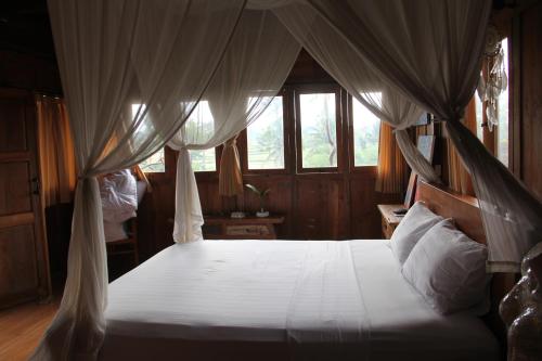 - une chambre avec un lit à baldaquin dans l'établissement Ogek Home Stay, à Ubud