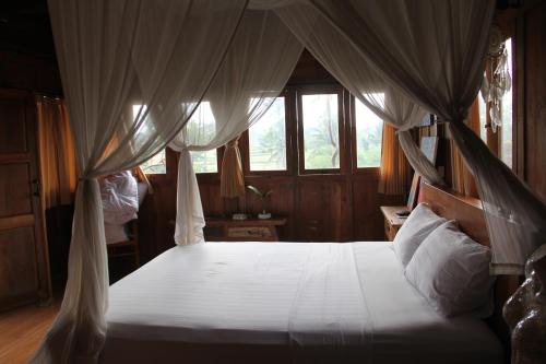 a bedroom with a bed with a canopy at Ogek Home Stay in Ubud