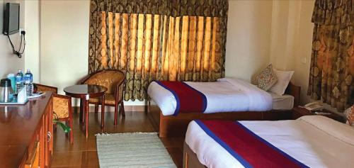 a hotel room with two beds and a table at Hotel Asia in Pokhara