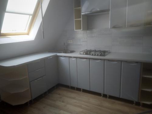 a kitchen with white cabinets and a sink and a window at Грушевського 13 in Berehove