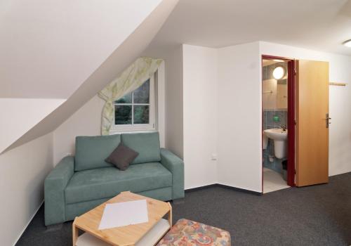 a living room with a green couch and a window at Pension Katty in Špindlerův Mlýn