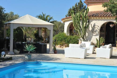 - une piscine avec des chaises blanches et un parasol blanc dans l'établissement Villa DESIDERIA B&B, à Capitana
