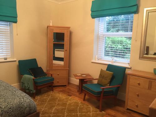 a bedroom with two chairs and a bed and a mirror at The Flat Frank Lewis House in Hay-on-Wye